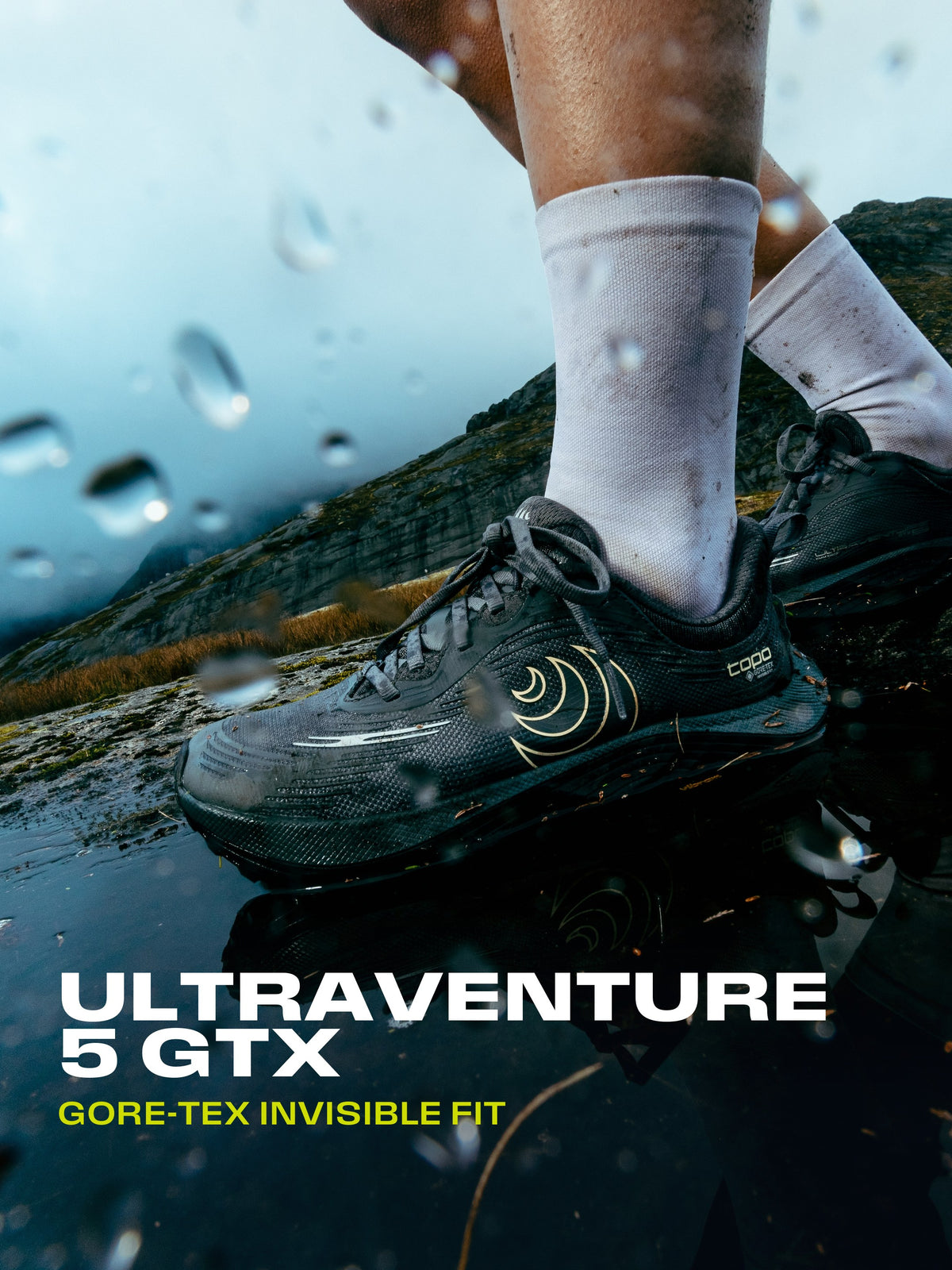Topo Athletic Ultraventure 5 GTX i en vattenpöl på en berghäll, i regn. Text: Ultraventure 5 GTX, GORE-TEX Invisible Fit